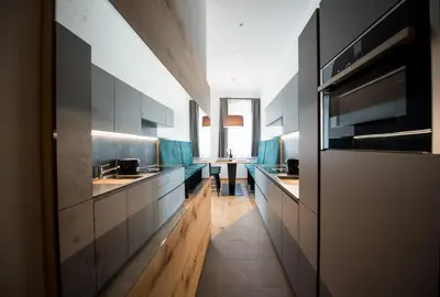 a large kitchen with blue chairs and a table at Apartments Windegg in Caldaro