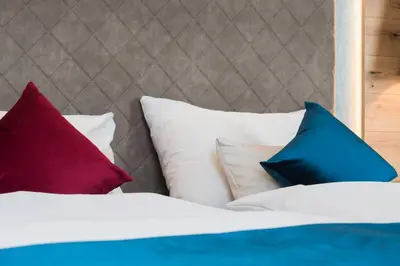 a bed with colorful pillows on it at Apartments Windegg in Caldaro