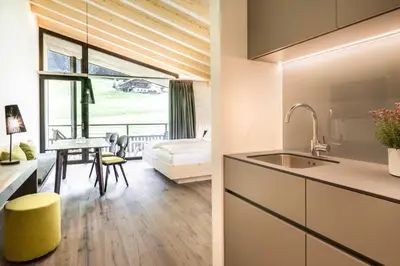 a bedroom with a table and chairs and a large window at Pra Palmer The Green B&B in Ortisei