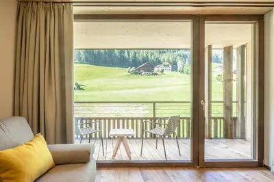 a room with two chairs and a table with mountains in the background at Pra Palmer The Green B&B in Ortisei