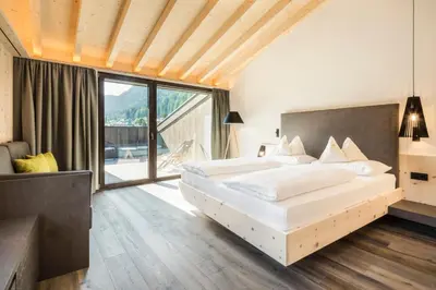 a bedroom with two beds and a large window at Pra Palmer The Green B&B in Ortisei
