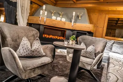 a living room with two chairs and a table and a fireplace at The Laurin Small & Charming in Selva di Val Gardena
