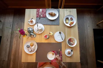 a person taking a picture of a table with plates of food at Hotel B&B Brunello in Ortisei