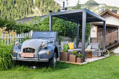 an old blue car parked in a yard with a gazebo at Hotel B&B Brunello in Ortisei