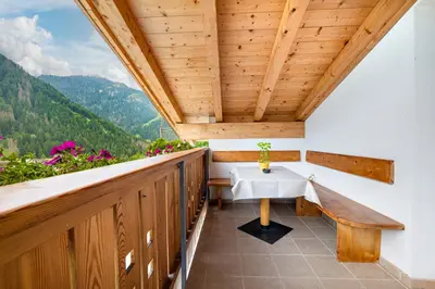 a balcony with a table and a bench at Hotel B&B Brunello in Ortisei