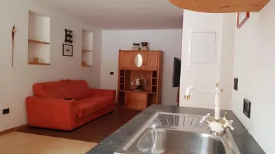 a kitchen with a sink and a red couch at Hotel B&B Brunello in Ortisei
