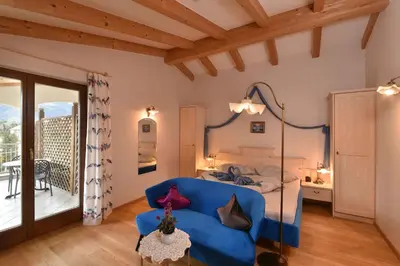 a bedroom with a blue couch and a bed at Residence Boutique Sonne in Schenna