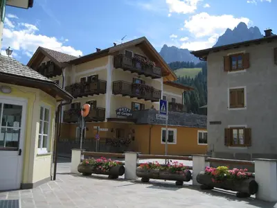 a large building with flowers in front of it at Hotel El Geiger in Pozza di Fassa
