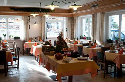 a dining room with tables and chairs and tablesktop at Hotel El Geiger in Pozza di Fassa