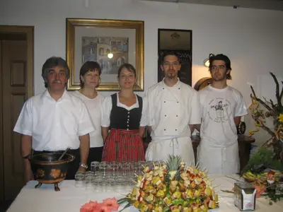 a group of people standing next to a table with food at Hotel El Geiger in Pozza di Fassa