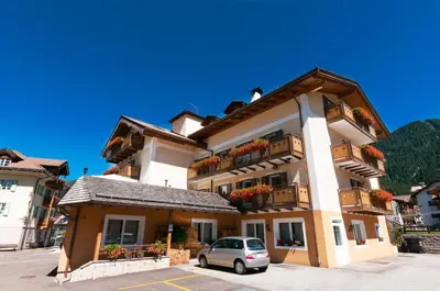 a building with a car parked in front of it at Hotel El Geiger in Pozza di Fassa