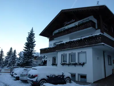 a snow covered building with cars parked in a parking lot at Garni Flurida in Selva di Val Gardena