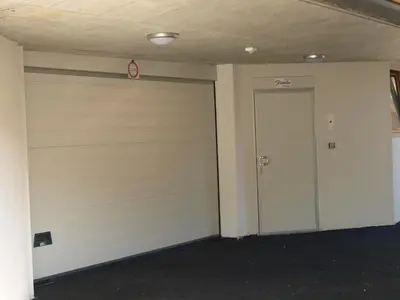 a garage with a white garage door and a doorway at Garni Flurida in Selva di Val Gardena