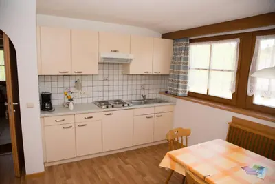 a kitchen with white cabinets and a table and a dining room at Stegerhof in Monguelfo