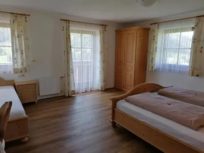 a bedroom with two beds and wooden floors and windows at Stegerhof in Monguelfo
