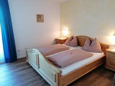 a bedroom with a wooden bed with two nightstands and two lamps at Stegerhof in Monguelfo