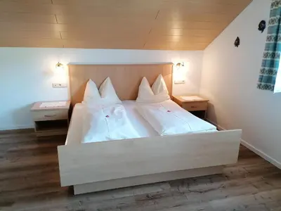 a bedroom with a large white bed with white pillows at Stegerhof in Monguelfo