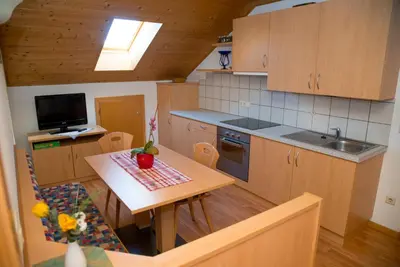 a kitchen with wooden cabinets and a table and a sink at Stegerhof in Monguelfo