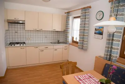 a kitchen with white cabinets and a table and a window at Stegerhof in Monguelfo