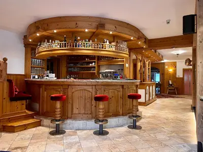 a large kitchen with a bar with red stools at Albergo Conturina in Canazei
