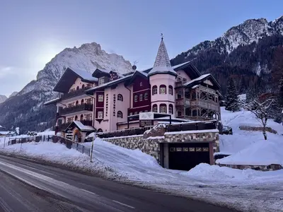 a large building on the side of a snow covered road at Albergo Conturina in Canazei