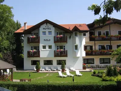 a hotel with lawn chairs and chairs in front of it at Hotel Al Polo in Ziano di Fiemme