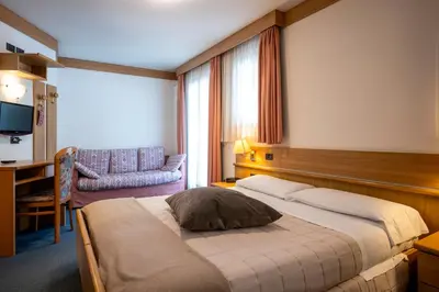 a hotel room with a bed and a chair at Hotel Al Polo in Ziano di Fiemme