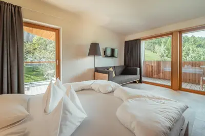 a bedroom with two beds and a couch and a window at Gailerhof Boutique Hotel B&B Dolomites in Monguelfo