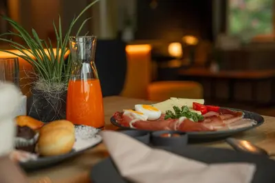 a table with plates of food and a bottle of orange juice at Gailerhof Boutique Hotel B&B Dolomites in Monguelfo