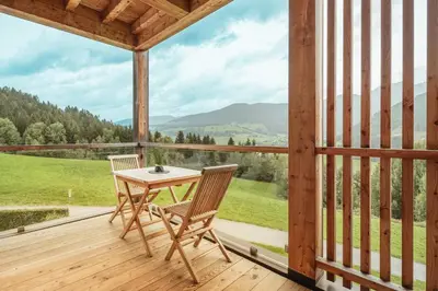 a wooden porch with a table and chairs on a deck at Gailerhof Boutique Hotel B&B Dolomites in Monguelfo