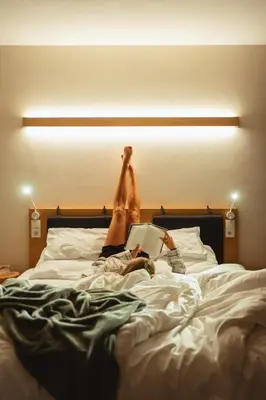 a person laying on a bed with their feet up at Gailerhof Boutique Hotel B&B Dolomites in Monguelfo