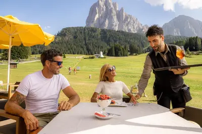 a group of three people sitting at a table at Monte Pana Dolomites Hotel in Santa Cristina in Val Gardena
