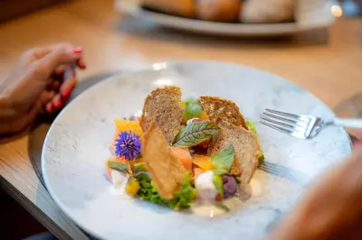 a white plate of food on a wooden table at Monte Pana Dolomites Hotel in Santa Cristina in Val Gardena