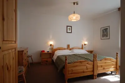 a bedroom with a wooden bed and two night stands at Hotel Ancora in Moena