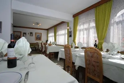 a restaurant with white tables and chairs and windows at Hotel Ancora in Moena