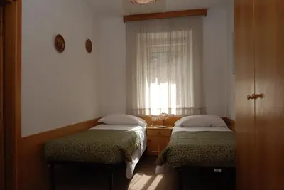 a small room with two beds and a window at Hotel Ancora in Moena
