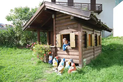a little boy sitting in the window of a toy house at Hotel Ancora in Moena