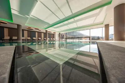 a swimming pool in a building with a large window at Hotel Cristal in Obereggen