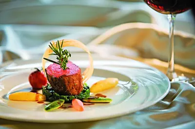 a plate of food on a table with a glass of wine at Hotel Cristal in Obereggen