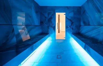 a corridor with a door in a room with blue lights at Hotel Cristal in Obereggen
