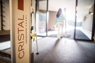 a woman walking down a hallway with a sign at Hotel Cristal in Obereggen
