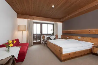 a bedroom with a large bed and a red couch at Hotel Ansitz Kematen ***S in Collalbo