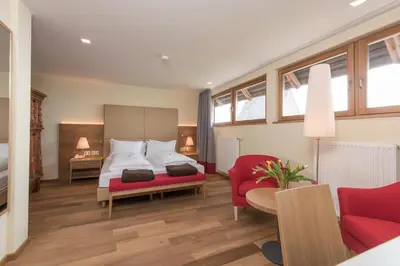 a bedroom with a bed and a red chair at Hotel Ansitz Kematen ***S in Collalbo