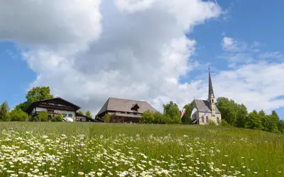 a field of flowers in front of a church at Hotel Ansitz Kematen ***S in Collalbo
