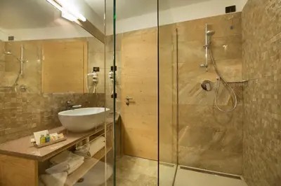 a bathroom with a glass shower and a sink at Chalet Marcora in Campitello di Fassa