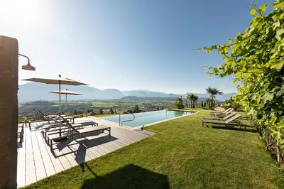 a swimming pool with a table and an umbrella at Mederle Hof in Appiano sulla Strada del Vino
