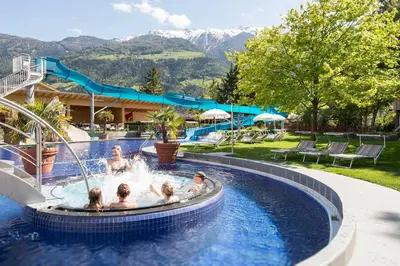 a group of people in a pool with a water slide at Hotel Prokulus - Family & Wellness in Naturno