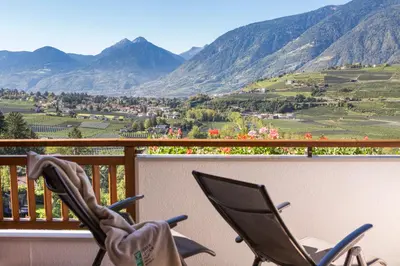 two chairs on a balcony with a view of mountains at Hotel Weingut Innerleiterhof in Schenna