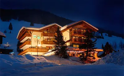 a large building in the snow at night at Hotel Dolomites Inn in Canazei