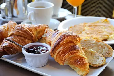 a plate of croissants and bread and a cup of coffee at Hotel Dolomites Inn in Canazei